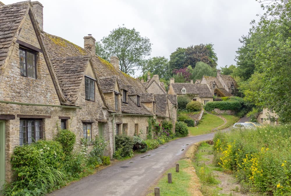 A honey-stone Cotswolds village street with a bridge over a stream